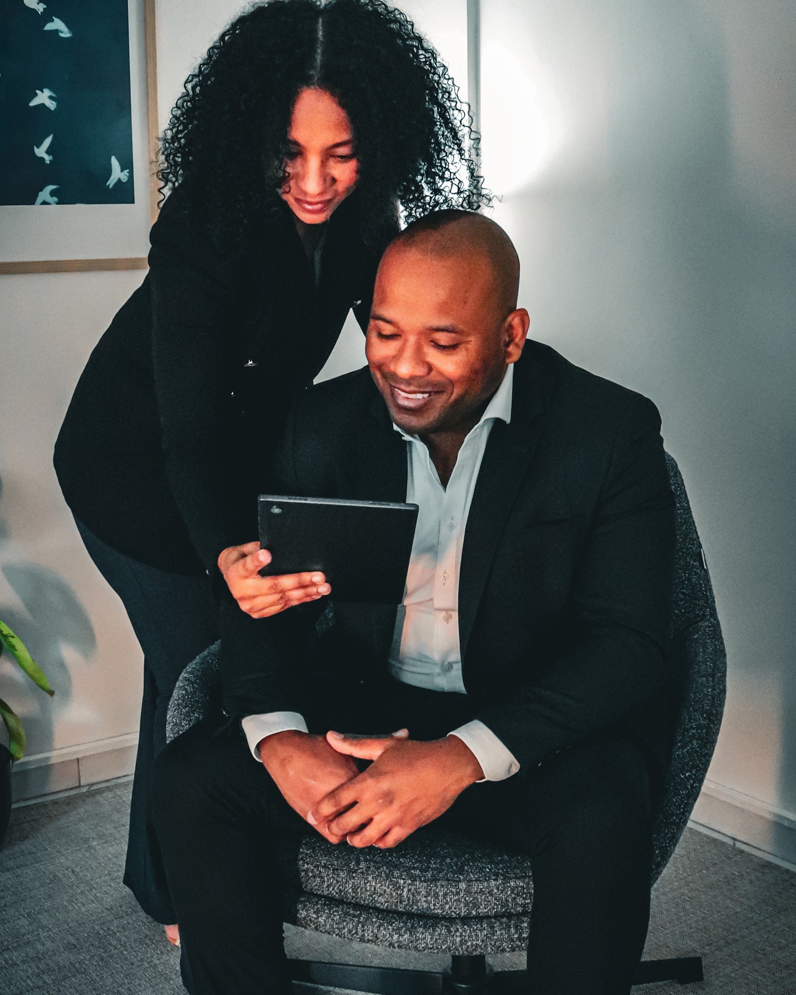 Os fundadores da Seguro Fácil sorrindo enquanto revisam uma cotação juntos em um tablet